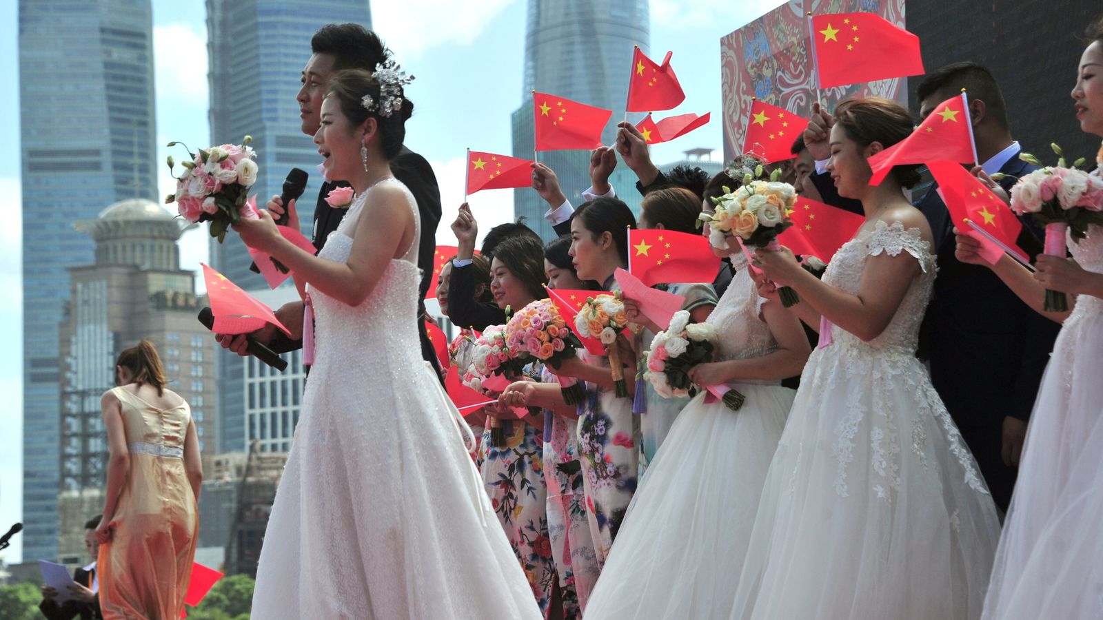 Couples holding Chinese flags sing as they attend a mass wedding on the Bund ahead of the 70th anniversary of People's Republic of China, in Shanghai, China September 19, 2019. REUTERS/Stringer ATTENTION EDITORS - THIS IMAGE WAS PROVIDED BY A THIRD PARTY. CHINA OUT.